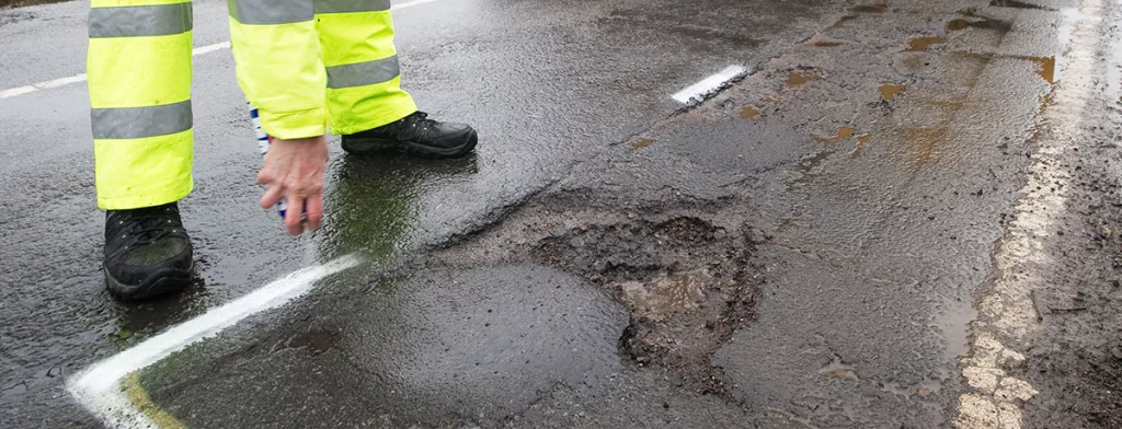 A worker highlighting potholes in asphalt